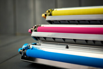 magenta, cyan and yellow toner for color laser printers stacked on gray wooden background