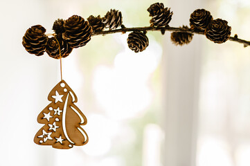 Christmas composition. Pine cones with Christmas wooden decorations on branches on light background. Side view, copy space. Layout made of winter. Holiday season concept.