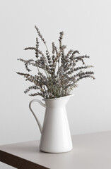 Lavender in a white vase on a beige table.