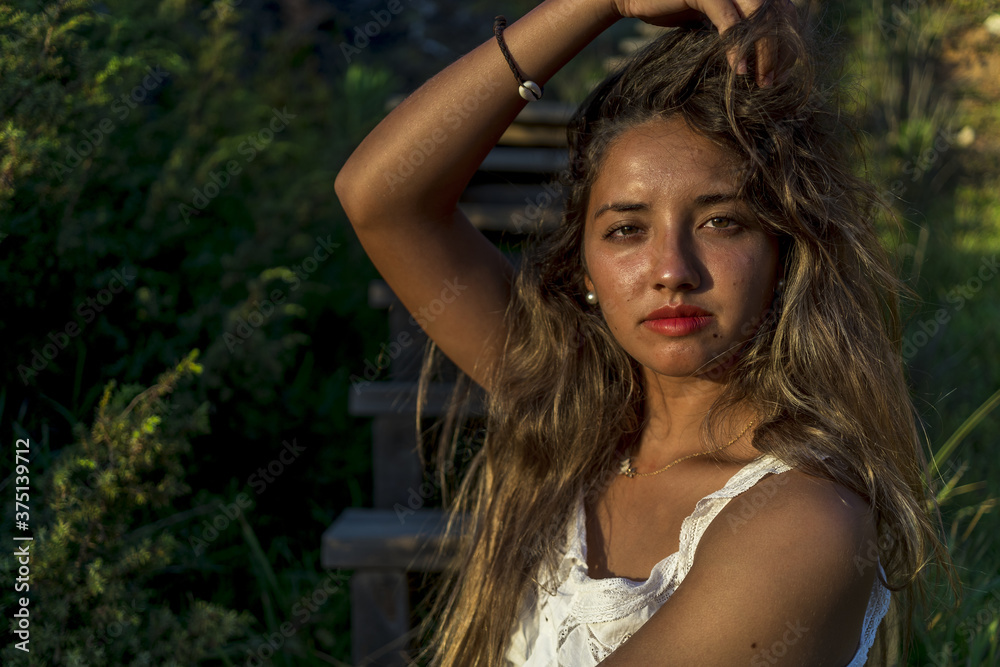 Poster closeup shot of a young lady with beautiful long hair happily posing for a photo on the beach