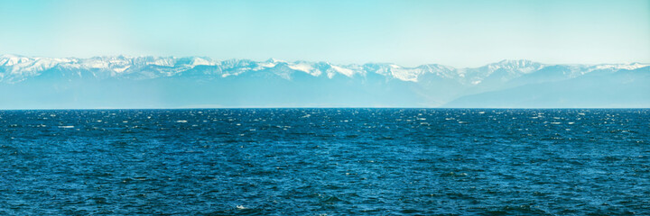 Fototapeta na wymiar Panorama of blue water of Lake Baikal, with mountain peaks against the sky of summer