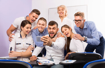 Happy positive students with female teacher making selfie indoors