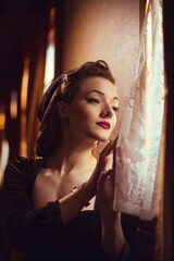young woman in vintage clothes looking out the window inside a retro train