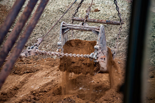 Aluminium ore quarry. Bauxite clay open-cut mining. Walking dragline excavator bucket with empty ground (spoil).