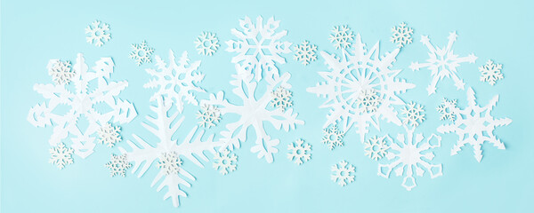 White Snowflakes cut from paper on blue background. A traditional Christmas arts and crafts easy diy project. Banner for your site, flyer, voucher, winter holiday concept