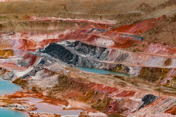 Aluminium ore quarry. Bauxite clay open-cut mining. Quarry steps of various color minerals. Blue quarry lake (left).