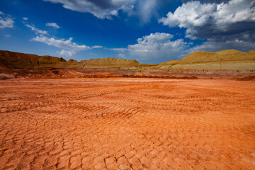 Fototapeta na wymiar Aluminium ore quarry. Bauxite clay open-cut mining. Truck trails on the ground. Green grass on the heaps. Blue sky with clouds. Panoramic view.