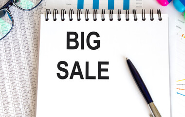 On a sheet of paper, the inscription BIG SALE is written to the letter tablet, next to the report.