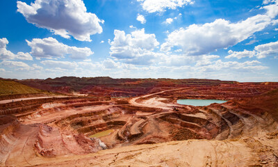 Aluminium ore quarry and blue lake in bauxite clay mine. Open cast (open-cut) mining. Panorama view. Blue sky with clouds in summer day. - obrazy, fototapety, plakaty