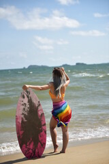 Sexy beautiful Asian surfer woman in bikini swimwear with surfboard on the beach/Extreme sport on summer holiday vacation