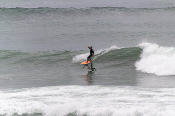 Surfers taking waves and resting in Barceloneta beach in Barcelona