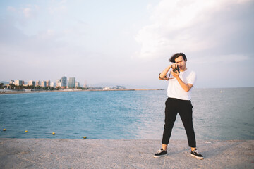 Cool hipster man taking photo against seafront