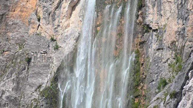Slow motion waterfall Boka, Slovenia. Water gently flowing down the rocks. Moss growing under waterfall. Static, close up