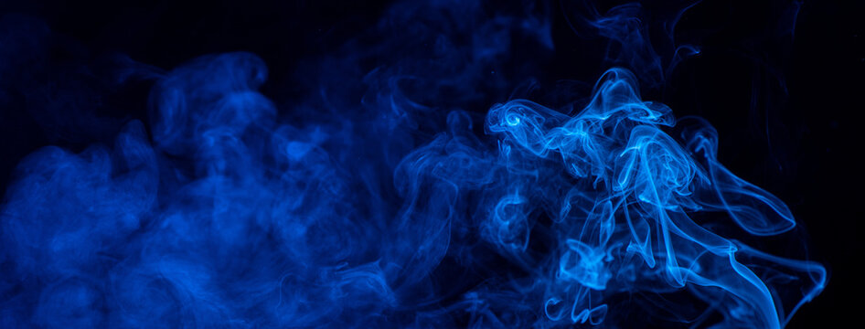 Conceptual image of blue color smoke isolated on dark black background, Halloween design element concept.