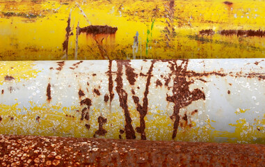 Detail of a weathered and rusted bright yellow steel pipes makes a banded abstract industrial background