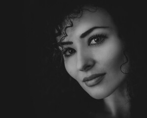 Beautiful young woman with curly hair looking sexy with half shadow on the face. Closeup portrait. Black and white Photography. 