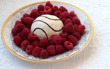 White plate with raspberries and sponge cake on a white background.