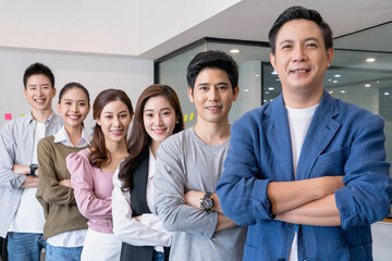 Happy Group portrait of young asian businesspeople standing indoors in office, looking at...