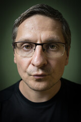 Studio portrait of serious 40 years old white (caucasian) man with glasses. Rembrandt lighting. 