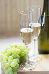 Two glasses with sparkling wine and grapes on light wooden background. Close-up. Selective focus.