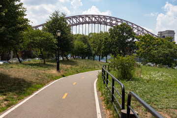 Astoria Queens Riverfront Trail at a Park with a view of the Hell Gate Bridge over the East River in New York City