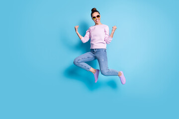Fototapeta na wymiar Full size photo of cheerful energetic girl jump celebrate luck discounts lottery win raise fists wear lilac violet sweater sneakers spectacles isolated over blue color background