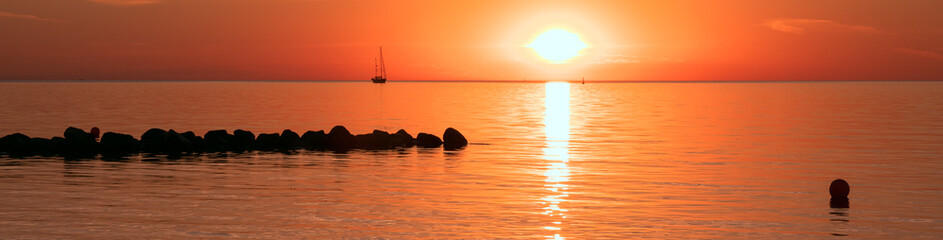 Fototapeta na wymiar Segelboot am Meer bei Sonnenaufgang, Panorama