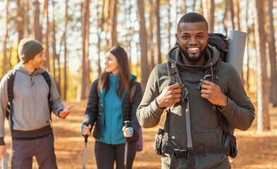 Fototapeta premium Happy black guy hiking with friends by countryside
