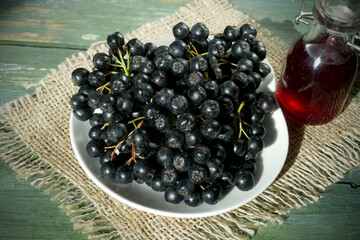 Fresh black chokeberry  (Aronia melanocarpa), juice in a bottle on a wooden background