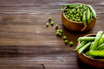 Set of green pea pods in wooden bowl on kitchen table desk