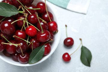 Sweet juicy cherries with leaves on grey marble table, top view