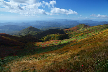 Fototapeta na wymiar カラフルに紅葉する栗駒山の登山コースから見える連なる山地と青空