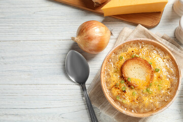 Tasty homemade french onion soup served on white wooden table, flat lay. Space for text