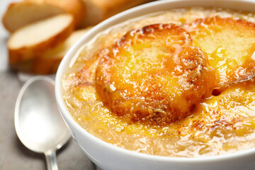 Tasty homemade french onion soup served in ceramic bowl, closeup