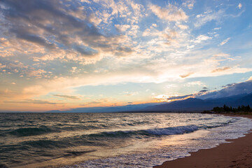 Obraz premium Beautiful sunset by the lake. Bright clouds are reflected in the water. Kyrgyzstan.