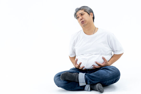 Portrait images of Asian obese men with gray hair are uses two hands to hold his belly, Which is full of own fat, and make a funny face, On white background to health care and fat man concept.