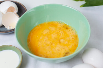 The process whisking egg yolks, making tasty egg omelet with green spinach for breakfast on white background. Idea recipe for a healthy diet food. Protein food for a vegetarian. Easy to cook.