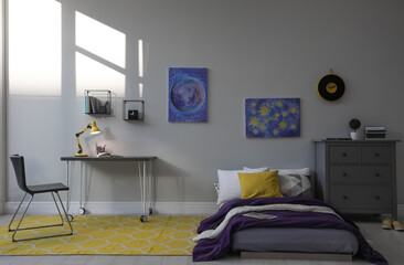 Modern teenager's room interior with comfortable bed, workplace and stylish design elements