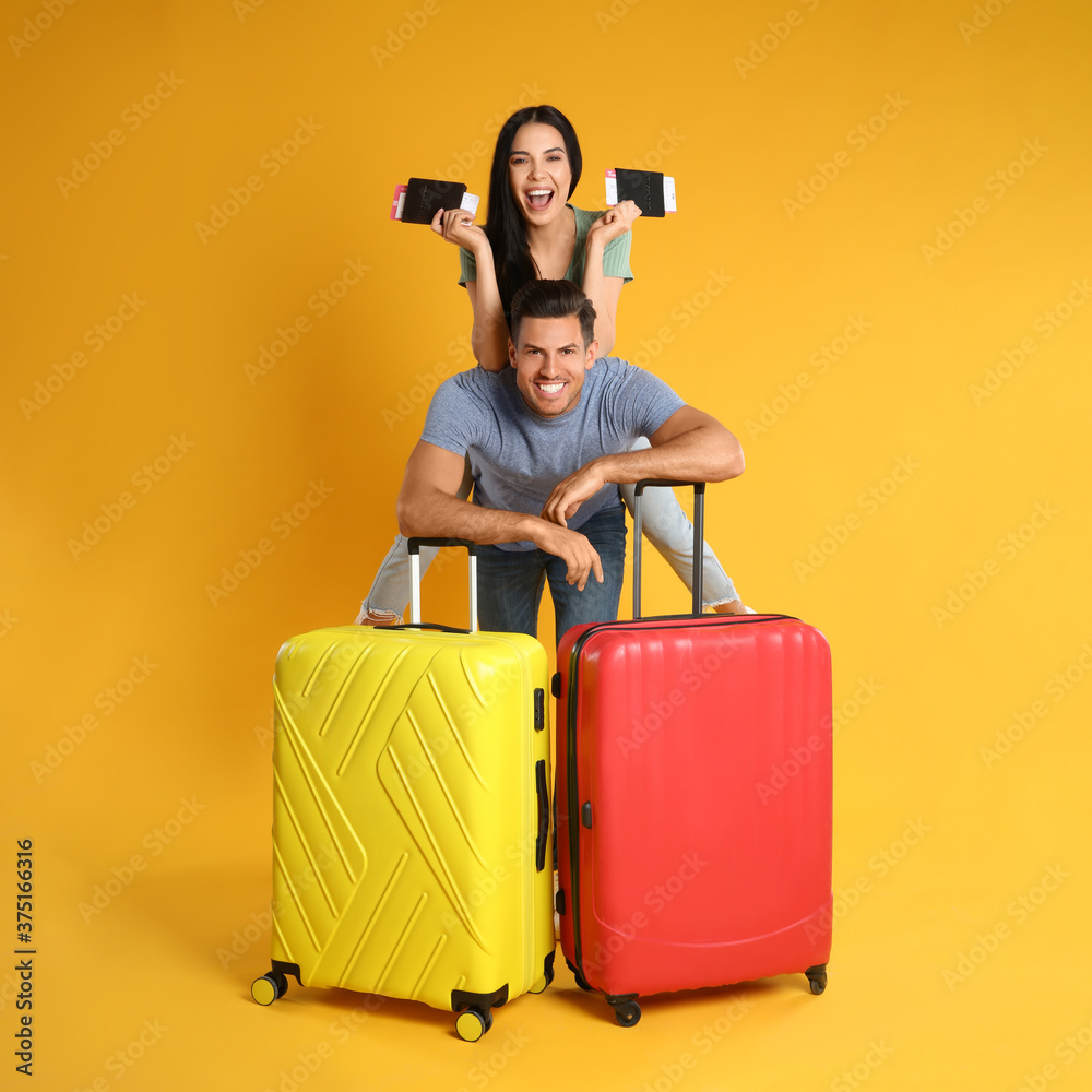 Wall mural happy couple with suitcases and passports for summer trip on yellow background. vacation travel