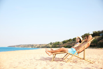 Couple resting on sunny beach at resort. Space for text