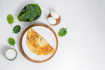 Tasty egg omelet with green leaves spinach on a white background. Top view. Idea recipe for healthy diet breakfast. Easy to cook. Protein food for a vegetarian. Free space for text.