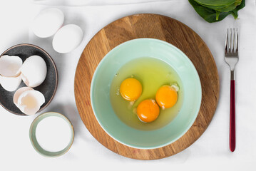 The process whisking egg yolks, making tasty egg omelet with green spinach for breakfast on white background. Idea recipe for a healthy diet food. Protein food for a vegetarian. Easy to cook.