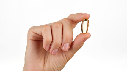 female hand holds in fingers capsule of Omega 3. Omega 3 gold fish oil capsule