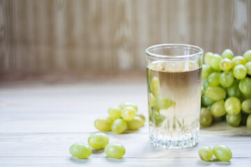A glass of grape juice with grapes on the table, selective focus. Copyspace.