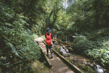 Obraz premium Ilan County, Taiwan - August 7th, 2020: A young female is walking on the famous Marian Hiking Trail, which is located above the Wufengqi Waterfall Scenic Area in Jiaoxi Township, Yilan County.