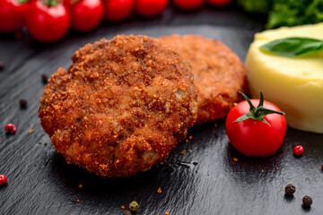 Cutlet with boiled potatoes on a black plate