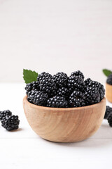 Fresh ripe blackberries in bowl on white wooden table. Space for text