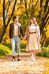 Fototapeta premium Full length portrait of young lovers in golden forest