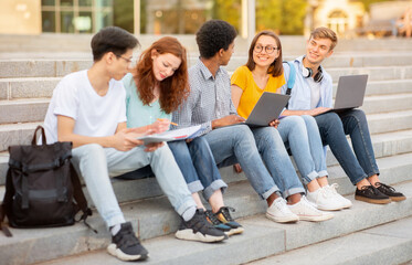 High-School Students Doing Homework Together Sitting On Steps Outside