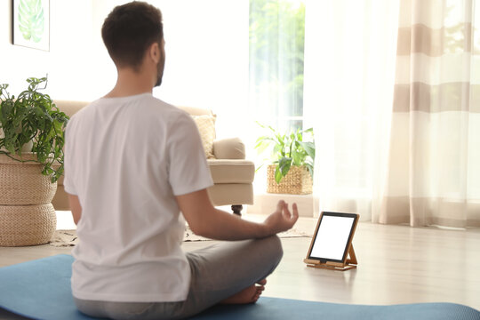 Man practicing yoga while watching online class at home during coronavirus pandemic. Social distancing